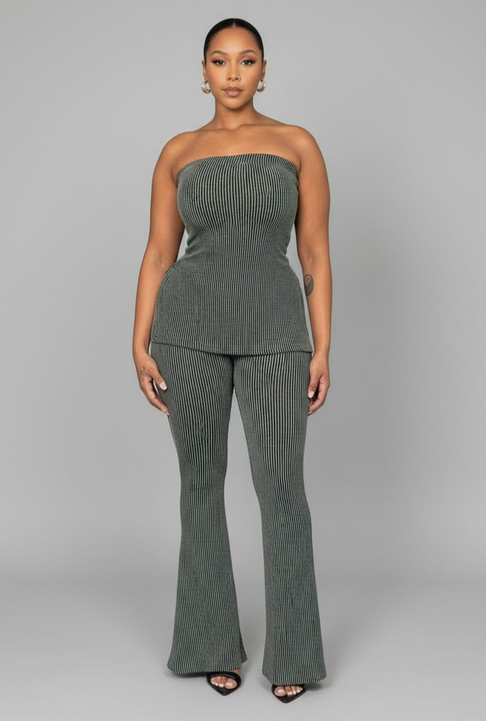 A woman standing in a room with green ribbed tube pants set, including a tube-style top and high-waisted pants.